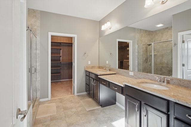 full bathroom featuring a sink, a shower stall, double vanity, and a spacious closet