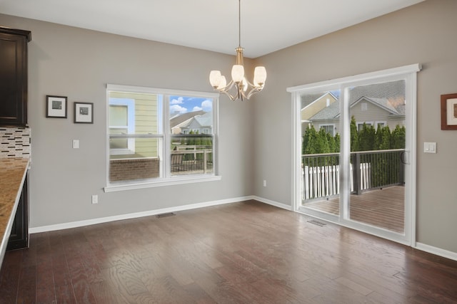 unfurnished dining area with an inviting chandelier, visible vents, a wealth of natural light, and dark wood-style floors