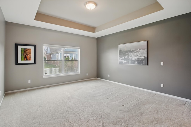 unfurnished room with visible vents, baseboards, carpet, and a raised ceiling