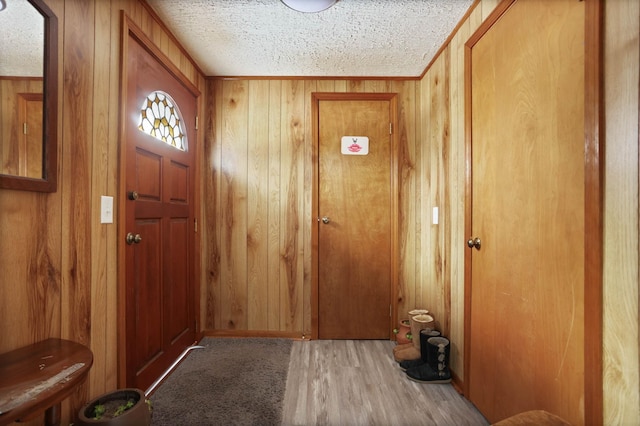 doorway to outside with wooden walls and a textured ceiling