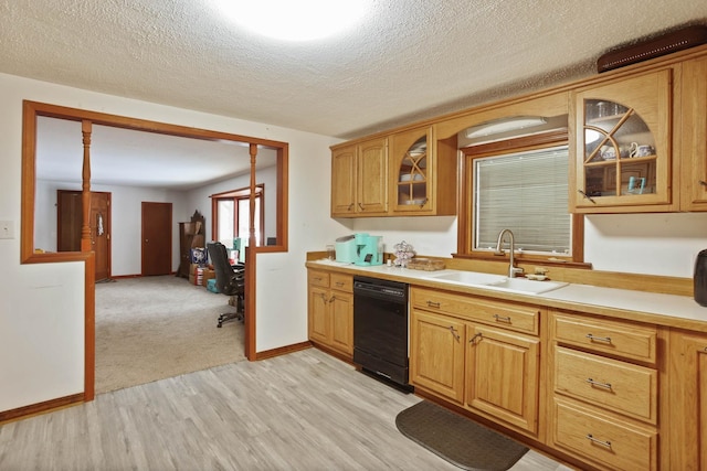 kitchen featuring light wood-type flooring, a sink, light countertops, glass insert cabinets, and black dishwasher