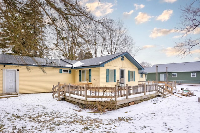 snow covered back of property featuring a deck and metal roof