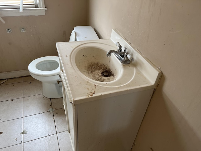 half bathroom with vanity, tile patterned floors, and toilet