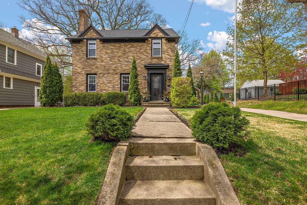 1215 Allerton Ave SE, Grand Rapids, MI 49506 - view of front of property with brick siding, a chimney, a front yard, and fence