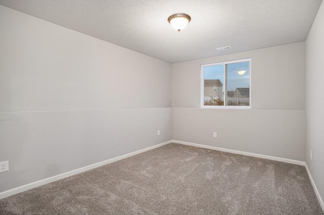 carpeted empty room featuring baseboards, a textured ceiling, and visible vents