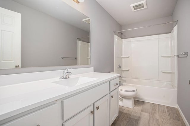 bathroom featuring visible vents, shower / tub combination, wood finished floors, vanity, and toilet
