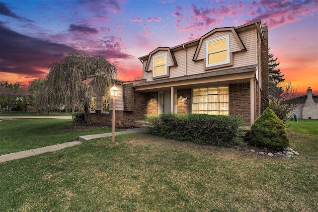 traditional-style house featuring brick siding and a front lawn