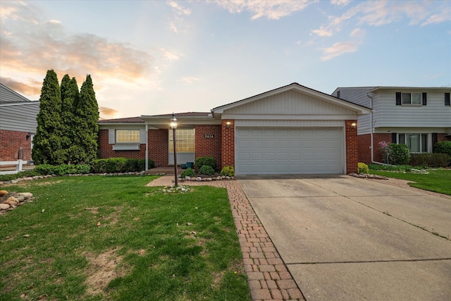 view of front facade with a yard, brick siding, driveway, and a garage