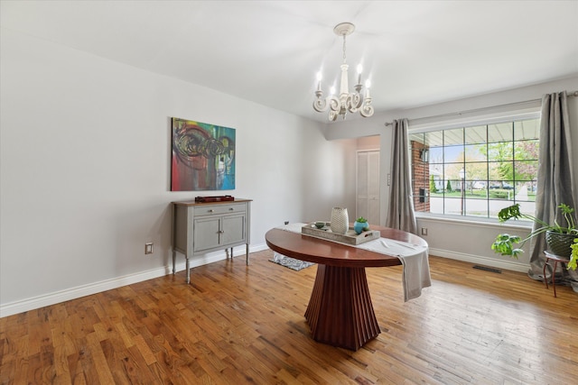 dining area with baseboards, an inviting chandelier, wood finished floors, and visible vents