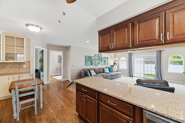 kitchen featuring stainless steel dishwasher, light stone countertops, light wood finished floors, and tasteful backsplash