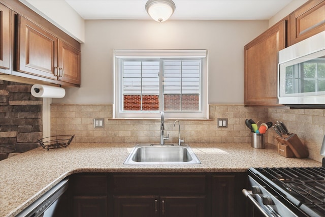 kitchen with decorative backsplash, brown cabinetry, appliances with stainless steel finishes, a sink, and light countertops