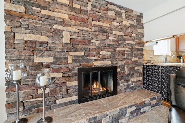 details featuring a sink, decorative backsplash, and a stone fireplace
