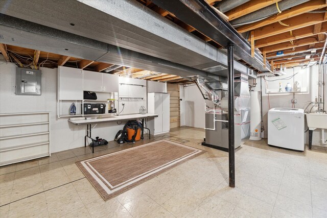 unfinished below grade area with water heater, washer / dryer, heating unit, light floors, and electric panel