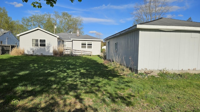 rear view of house featuring fence and a yard