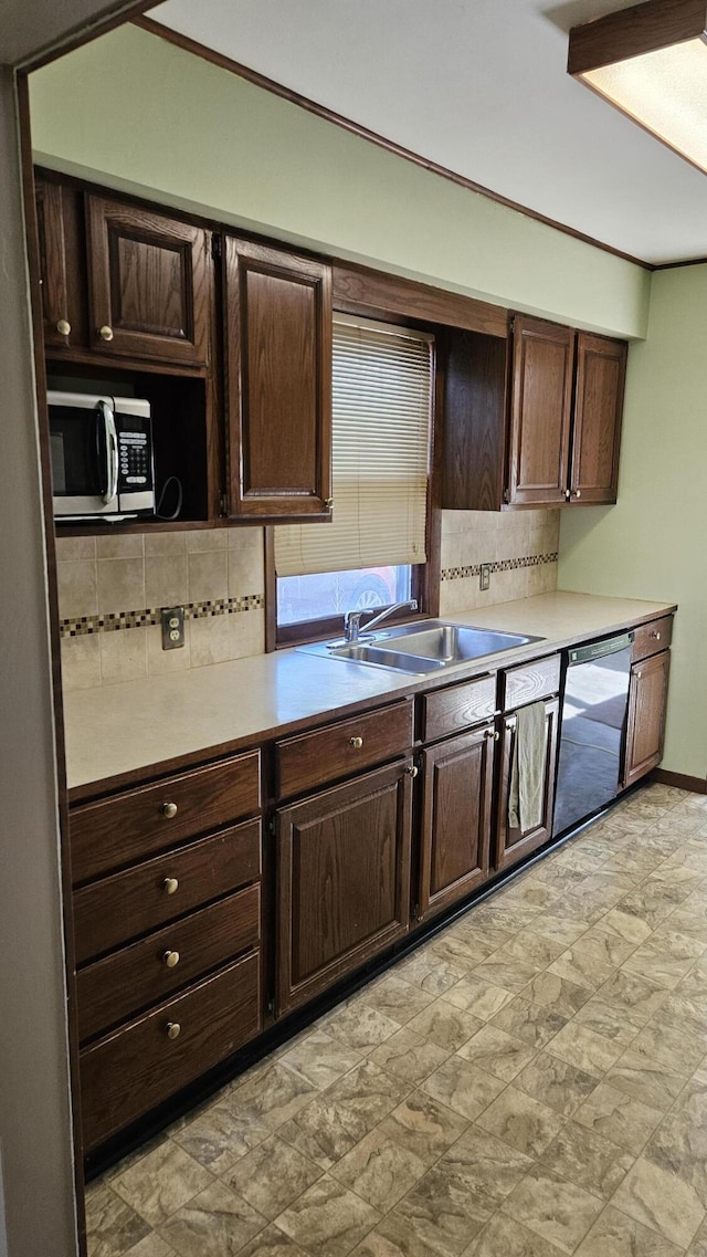 kitchen with a sink, stainless steel microwave, backsplash, and light countertops
