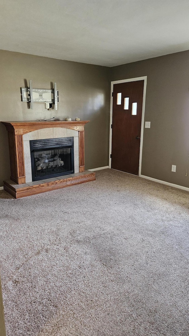 unfurnished living room with baseboards, carpet floors, and a tile fireplace