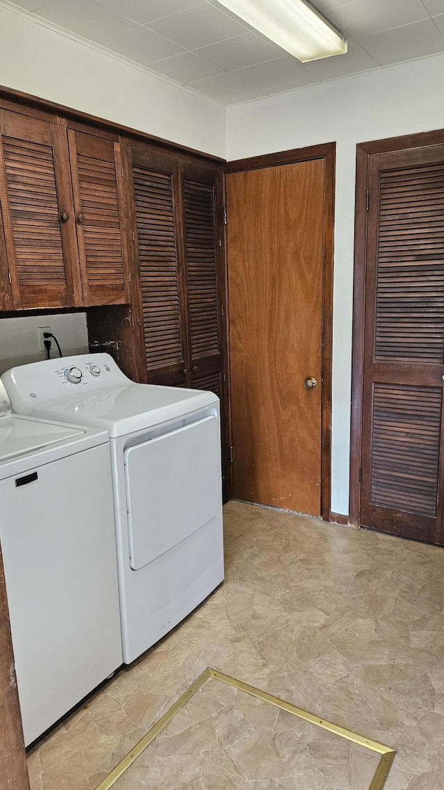 clothes washing area featuring separate washer and dryer and cabinet space