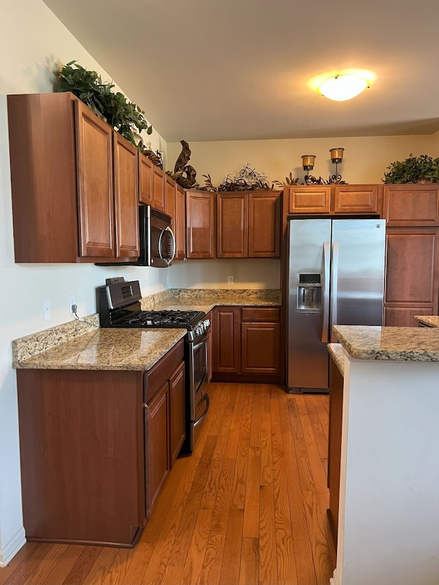 1082 Paddock Dr Unit 78, South Lyon, MI 48178 - kitchen featuring stainless steel appliances, light stone counters, and light wood finished floors