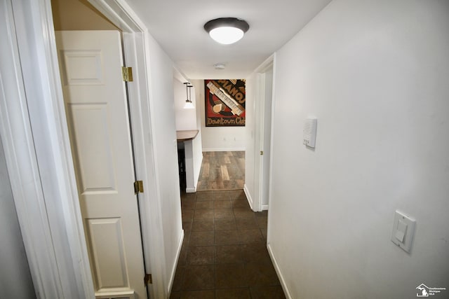 corridor featuring dark tile patterned flooring and baseboards