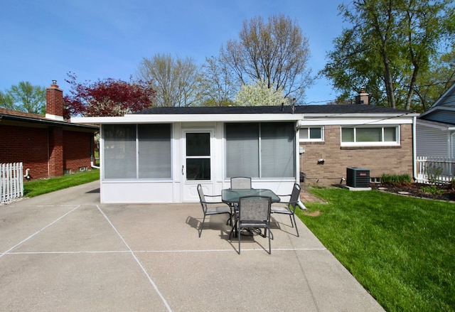 rear view of house with brick siding, central AC unit, a chimney, a patio area, and a lawn