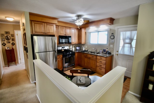 kitchen featuring ceiling fan, brown cabinetry, appliances with stainless steel finishes, tasteful backsplash, and a sink
