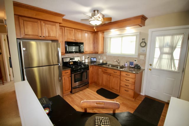 kitchen featuring dark countertops, ceiling fan, a sink, appliances with stainless steel finishes, and backsplash