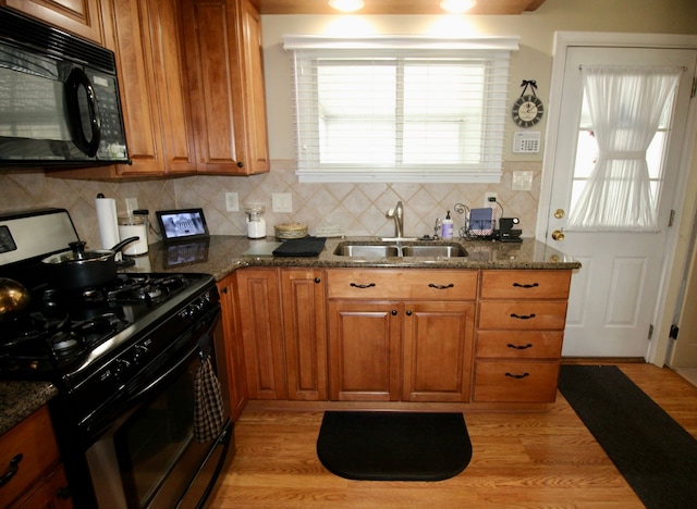 kitchen with black microwave, stainless steel range with gas stovetop, brown cabinets, and a sink