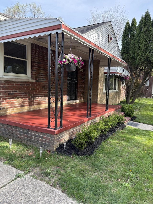 view of property exterior featuring a porch, brick siding, and a lawn