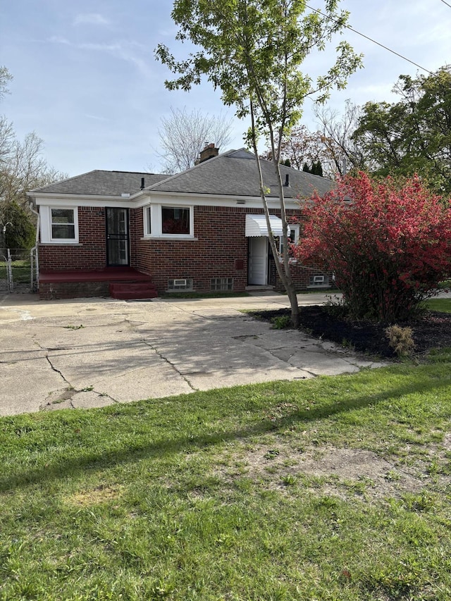 view of front of house featuring brick siding, a front lawn, and a chimney