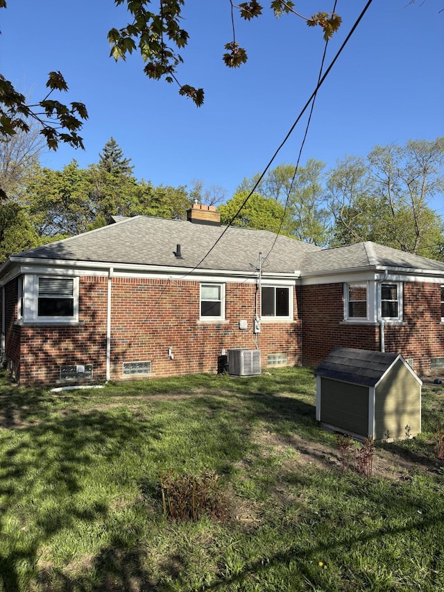 back of house featuring a storage shed, brick siding, a chimney, and an outdoor structure