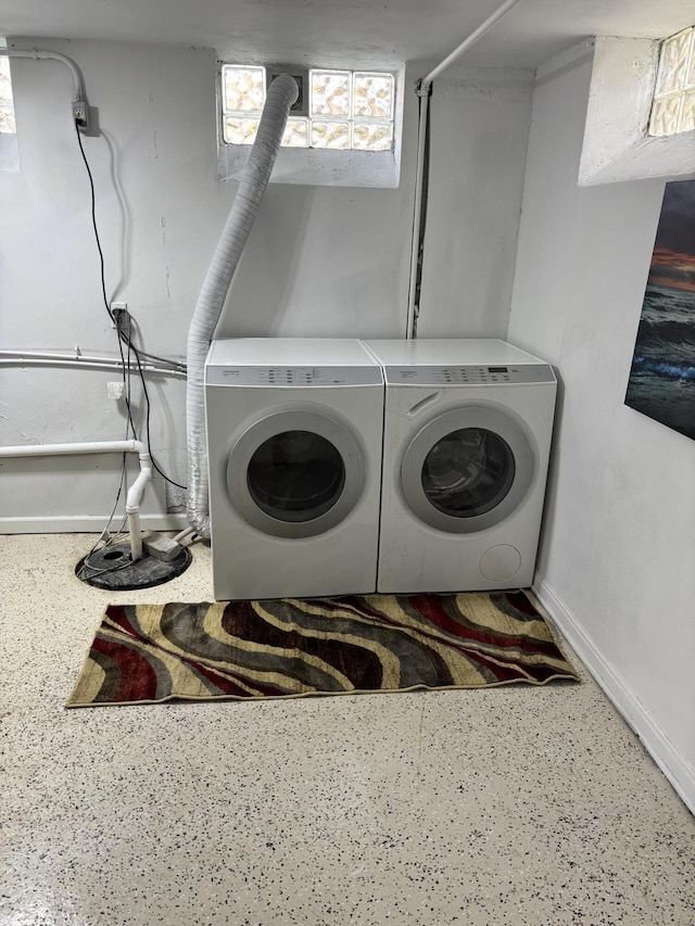 washroom with baseboards and washing machine and clothes dryer