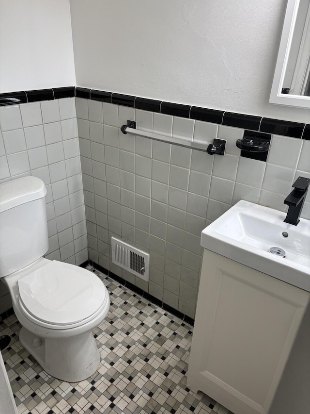 bathroom with tile walls, vanity, toilet, and visible vents