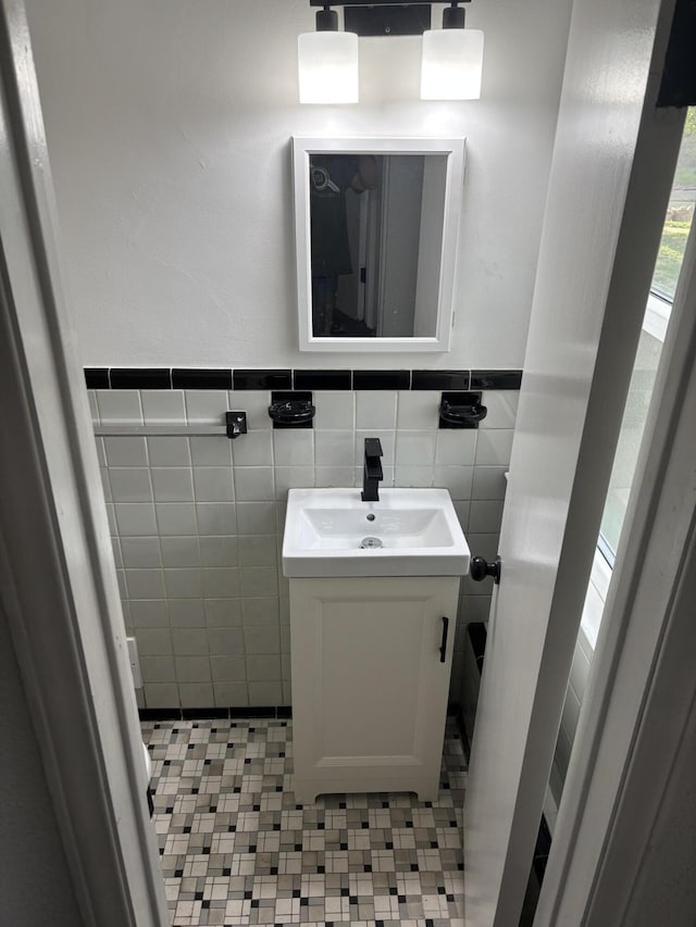 half bathroom featuring vanity, a wainscoted wall, and tile walls