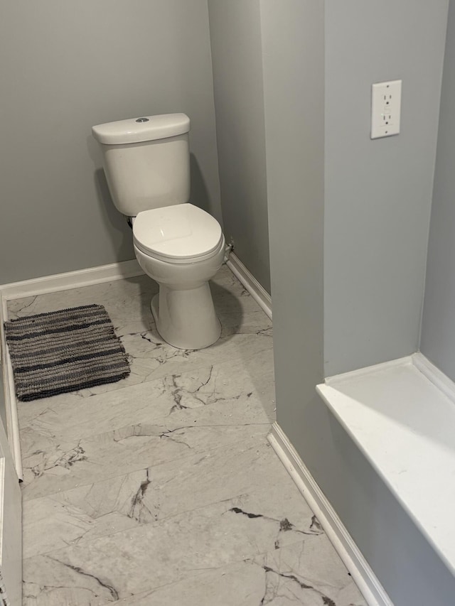 bathroom with baseboards, marble finish floor, and toilet