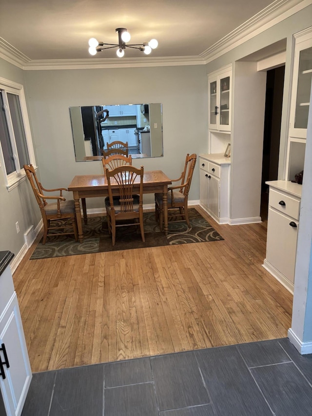 dining space featuring baseboards, visible vents, ornamental molding, and light wood finished floors