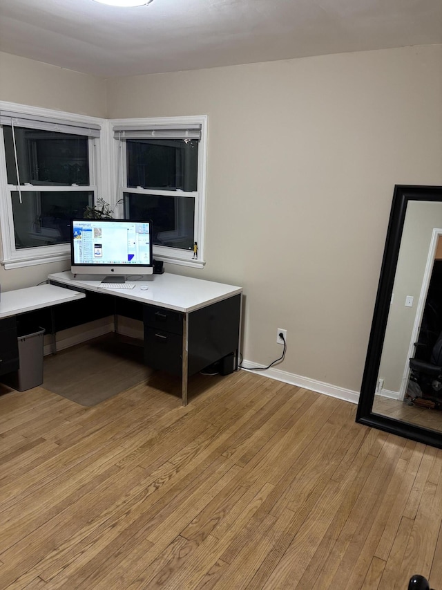 office space featuring built in study area, light wood-style floors, and baseboards