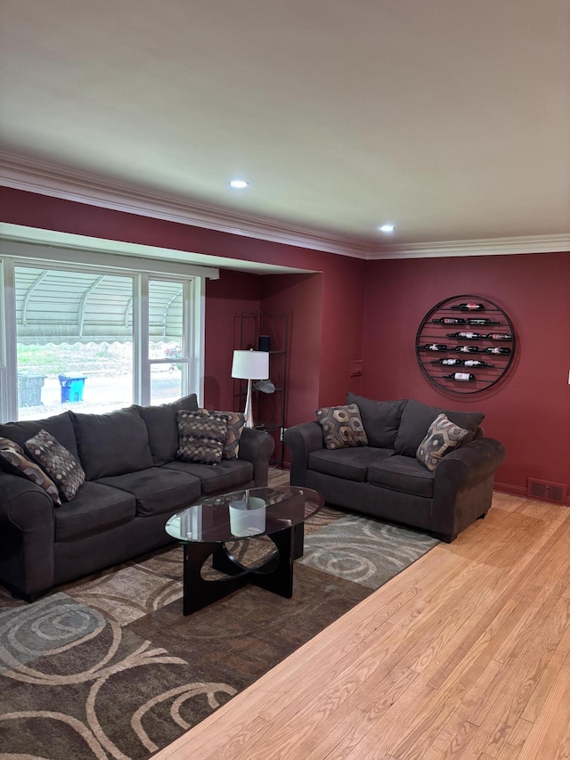 living room with crown molding, wood finished floors, and visible vents