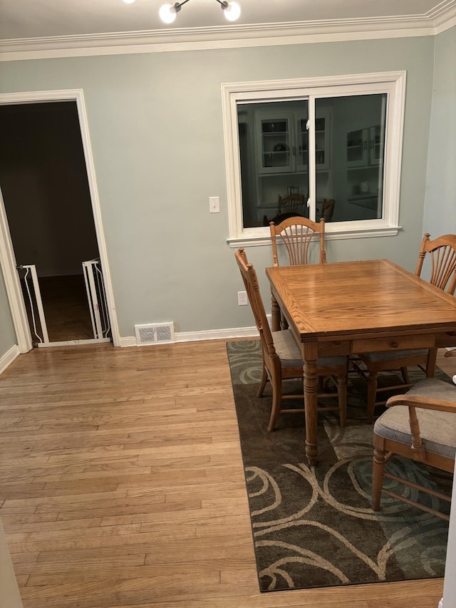 dining room featuring baseboards, visible vents, ornamental molding, and wood finished floors