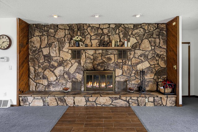interior details featuring visible vents, a textured ceiling, wood finished floors, and a fireplace