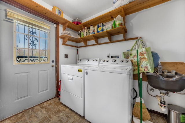laundry room with laundry area, washer and clothes dryer, stone finish flooring, and a sink