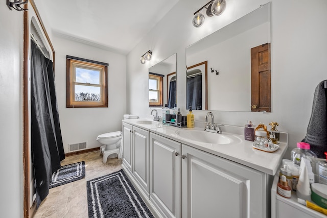 bathroom featuring double vanity, toilet, visible vents, and a sink