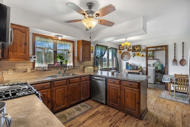 kitchen featuring stainless steel dishwasher, washer / dryer, a peninsula, a sink, and backsplash