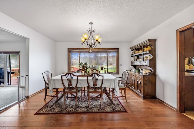 dining space featuring a textured ceiling, a chandelier, and wood finished floors