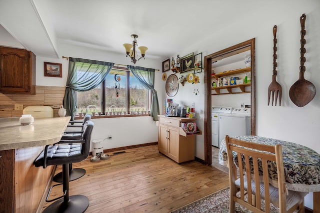 dining space with visible vents, an inviting chandelier, baseboards, light wood-type flooring, and separate washer and dryer