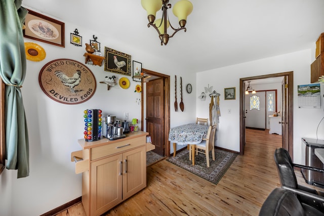 dining area with baseboards, a notable chandelier, and light wood-style floors