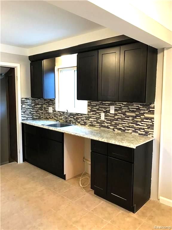 8404 Westminster Ave, Warren, MI 48089 - kitchen with a sink, backsplash, light countertops, and dark cabinets