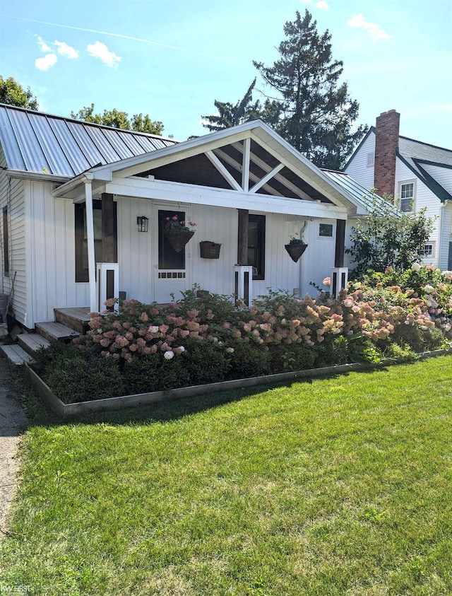 view of front facade with board and batten siding, metal roof, and a front yard