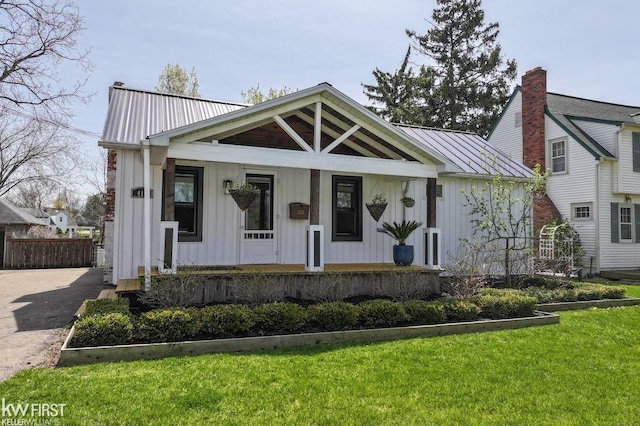 modern farmhouse style home featuring a porch, board and batten siding, metal roof, and a front lawn