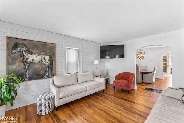 living room with arched walkways and wood finished floors