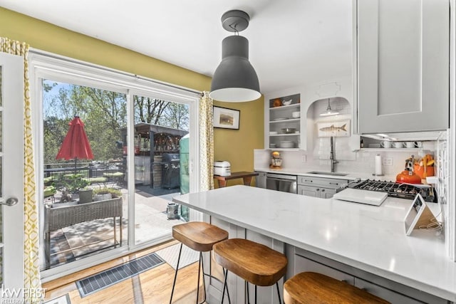 kitchen with a peninsula, dishwasher, a kitchen breakfast bar, a sink, and backsplash